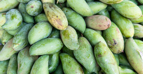 green mangoes lying on a market counter. Exotic fruits of Asia