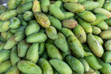 green mangoes lying on a market counter. Exotic fruits of Asia