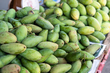 green mangoes lying on a market counter. Exotic fruits of Asia