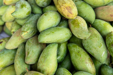 green mangoes lying on a market counter. Exotic fruits of Asia