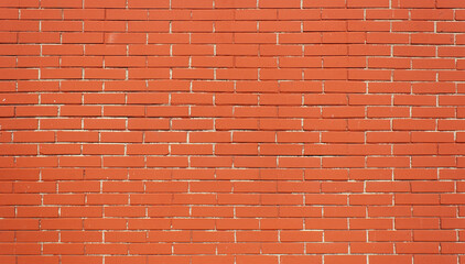 Background of red brick texture. Brown brick wall with white uneven seam. Building pattern. The construction of a stone wall. Old concrete fence with a shadow from the sun. For design.