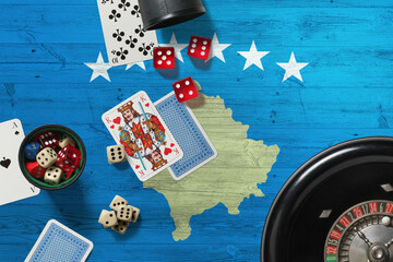 Kosovo casino theme. Aces in poker game, cards and chips on red table with national wooden flag background. Gambling and betting.
