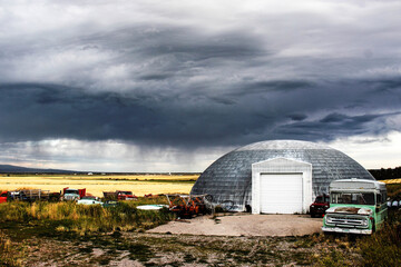 dome and a green truck in front of a crop field under the cloudy sky