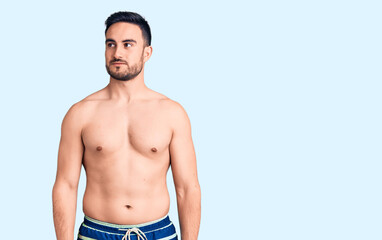 Fototapeta na wymiar Young handsome man wearing swimwear smiling looking to the side and staring away thinking.