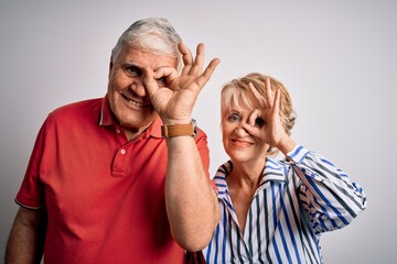 Senior beautiful couple standing together over isolated white background doing ok gesture with hand smiling, eye looking through fingers with happy face.