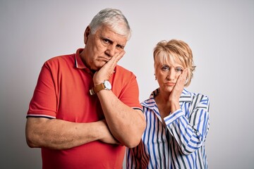 Senior beautiful couple standing together over isolated white background thinking looking tired and bored with depression problems with crossed arms.