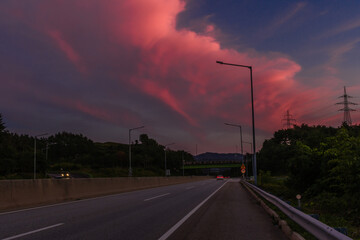 Fototapeta na wymiar Large pink clouds over highway