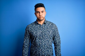 Young handsome man wearing casual shirt standing over isolated blue background puffing cheeks with funny face. Mouth inflated with air, crazy expression.