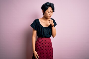 Young beautiful asian girl wearing casual dress standing over isolated pink background feeling unwell and coughing as symptom for cold or bronchitis. Health care concept.