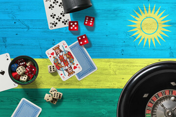 Rwanda casino theme. Aces in poker game, cards and chips on red table with national wooden flag background. Gambling and betting.