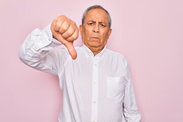 Senior handsome grey-haired man wearing elegant shirt over isolated pink background looking unhappy and angry showing rejection and negative with thumbs down gesture. Bad expression.