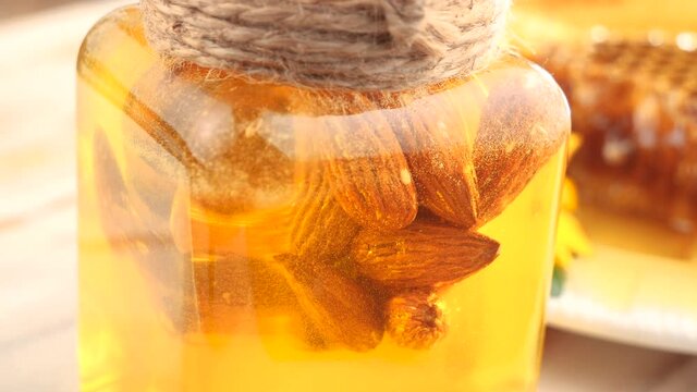 Sweet bee honey is mixed with a honey stick in a glass jar 