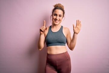 Young beautiful blonde sportswoman doing sport wearing sportswear over pink background showing and pointing up with fingers number six while smiling confident and happy.