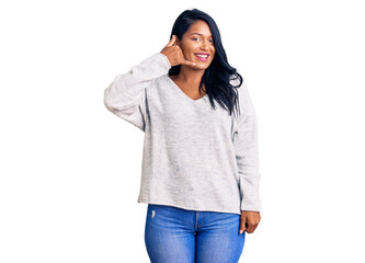 Hispanic woman with long hair wearing casual clothes smiling doing phone gesture with hand and fingers like talking on the telephone. communicating concepts.