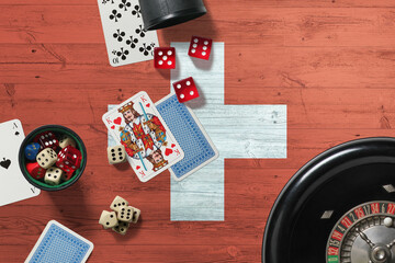 Switzerland casino theme. Aces in poker game, cards and chips on red table with national wooden flag background. Gambling and betting.