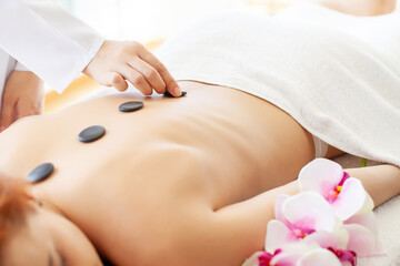 Spa stone massage, beautiful woman getting spa hot stones massage in spa salon.