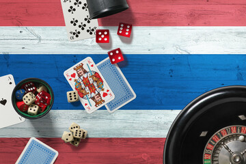 Thailand casino theme. Aces in poker game, cards and chips on red table with national wooden flag background. Gambling and betting.