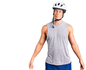 Young handsome man wearing bike helmet making fish face with lips, crazy and comical gesture. funny expression.