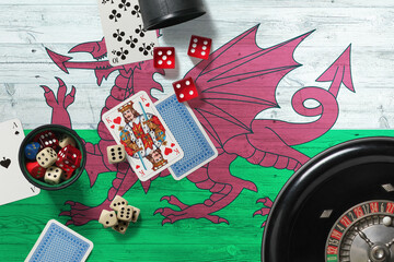 Wales casino theme. Aces in poker game, cards and chips on red table with national wooden flag background. Gambling and betting.