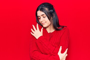 Young beautiful girl wearing casual sweater hugging oneself happy and positive, smiling confident....