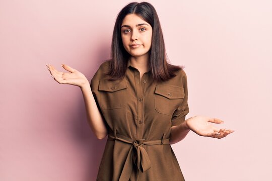 Young beautiful girl wearing casual dress clueless and confused with open arms, no idea and doubtful face.