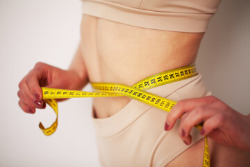 Woman with a sporty figure measures the size of her waist