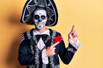 Young man wearing mexican day of the dead costume over yellow smiling and looking at the camera...