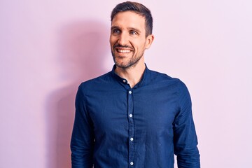 Young handsome man wearing casual shirt standing over isolated pink background looking to side, relax profile pose with natural face and confident smile.