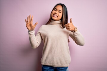 Young beautiful asian girl wearing casual turtleneck sweater over isolated pink background showing and pointing up with fingers number six while smiling confident and happy.
