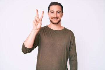 Young handsome man wearing casual clothes showing and pointing up with fingers number two while smiling confident and happy.