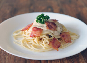 Delicious spaghetti carbonara with bacon on wooden table