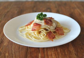 Delicious spaghetti carbonara with bacon on wooden table