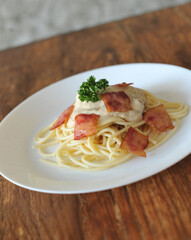 Delicious spaghetti carbonara with bacon on wooden table