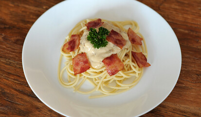 Delicious spaghetti carbonara with bacon on wooden table