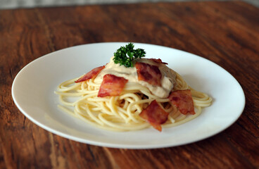 Delicious spaghetti carbonara with bacon on wooden table