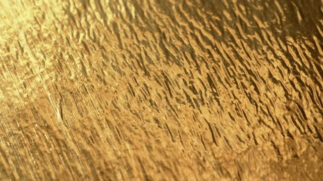 Gold foil texture background. Macro shot of rotation of golden surface