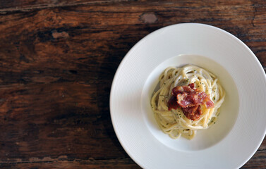 Delicious spaghetti carbonara with bacon on wooden table