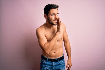 Young handsome strong man with beard shirtless standing over isolated pink background hand on mouth telling secret rumor, whispering malicious talk conversation