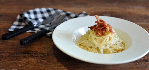 Delicious spaghetti carbonara with bacon on wooden table