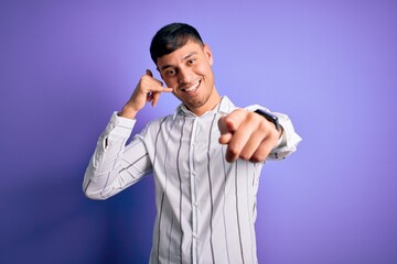 Young handsome hispanic man wearing elegant business shirt standing over purple background smiling...