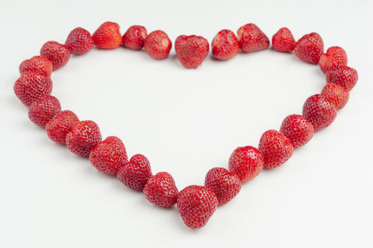 heart is laid out of strawberries on a white background