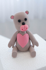 Teddy bear with pink heart cake topper, cute edible decoration made out of colorful sugar paste or...