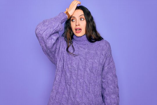 Young beautiful woman wearing casual turtleneck sweater standing over purple background surprised with hand on head for mistake, remember error. Forgot, bad memory concept.