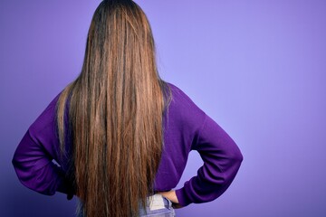 Young beautiful smart woman wearing glasses over purple isolated background standing backwards...
