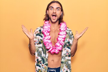 Young handsome man wearing swimwear and hawaiian lei celebrating victory with happy smile and...