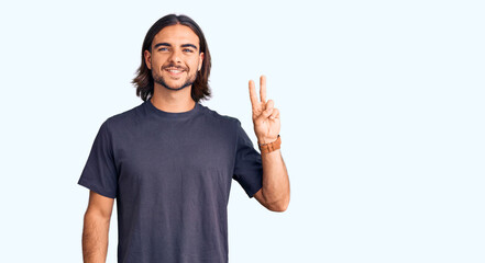 Young handsome man wearing casual clothes smiling with happy face winking at the camera doing victory sign. number two.