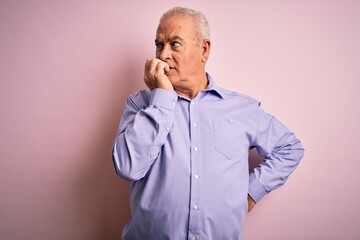 Middle age handsome hoary man wearing casual shirt standing over pink background looking stressed and nervous with hands on mouth biting nails. Anxiety problem.
