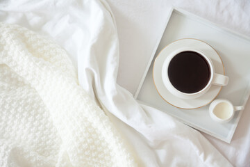 Cozy breakfast in bed, cup of coffee and milk on the grey fabric, space for text. Alarm clock for...