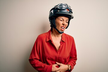Middle age motorcyclist woman wearing motorcycle helmet over isolated white background with hand on stomach because nausea, painful disease feeling unwell. Ache concept.