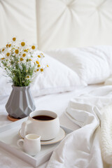 Cozy breakfast in bed, cup of coffee and milk on the grey fabric, space for text. Alarm clock for seven in the morning.